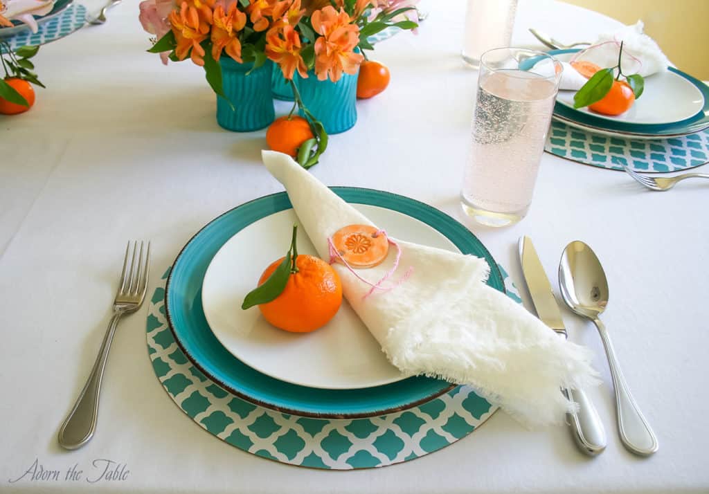 Mother's day table setting. Teal and white diy charger, teal plate, white linen napkin and orange diy napkin ring. With diy tinted teal vases filled with orange and pink flowers.