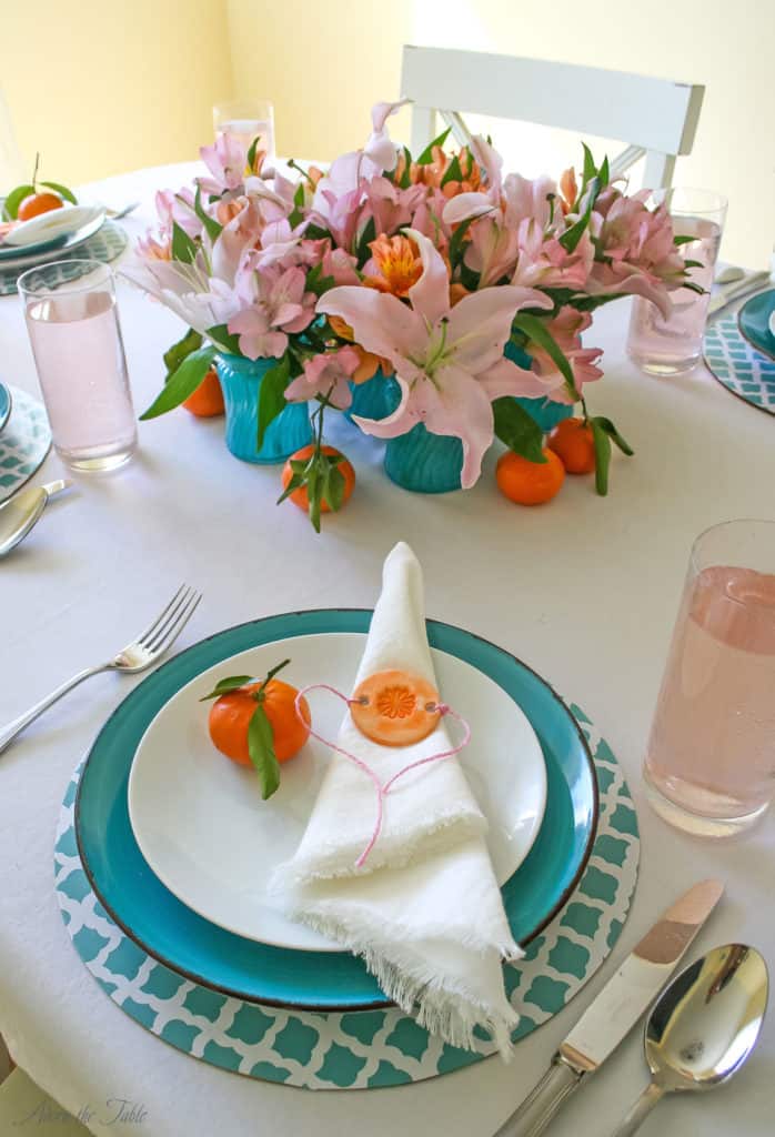 Mother's day table setting. Teal and white diy charger, teal plate, white linen napkin and orange diy napkin ring. With diy tinted teal vases filled with orange and pink flowers.