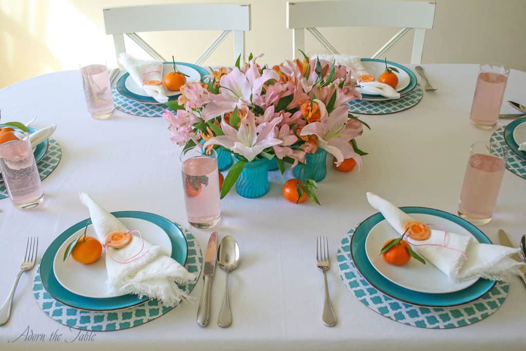 Centerpieces three ways - table setting close up of 6 teal diy vases in the middle of the table with pink and orange flowers