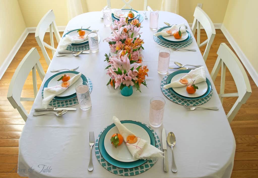 Centerpieces three ways - table setting showing 6 vases lined up in a row. Teal, orange and pink theme colors.
