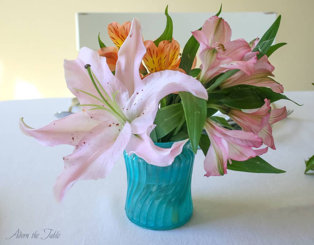 Mother's Day centerpiece of teal diy tinted vases, orange and pink flowers