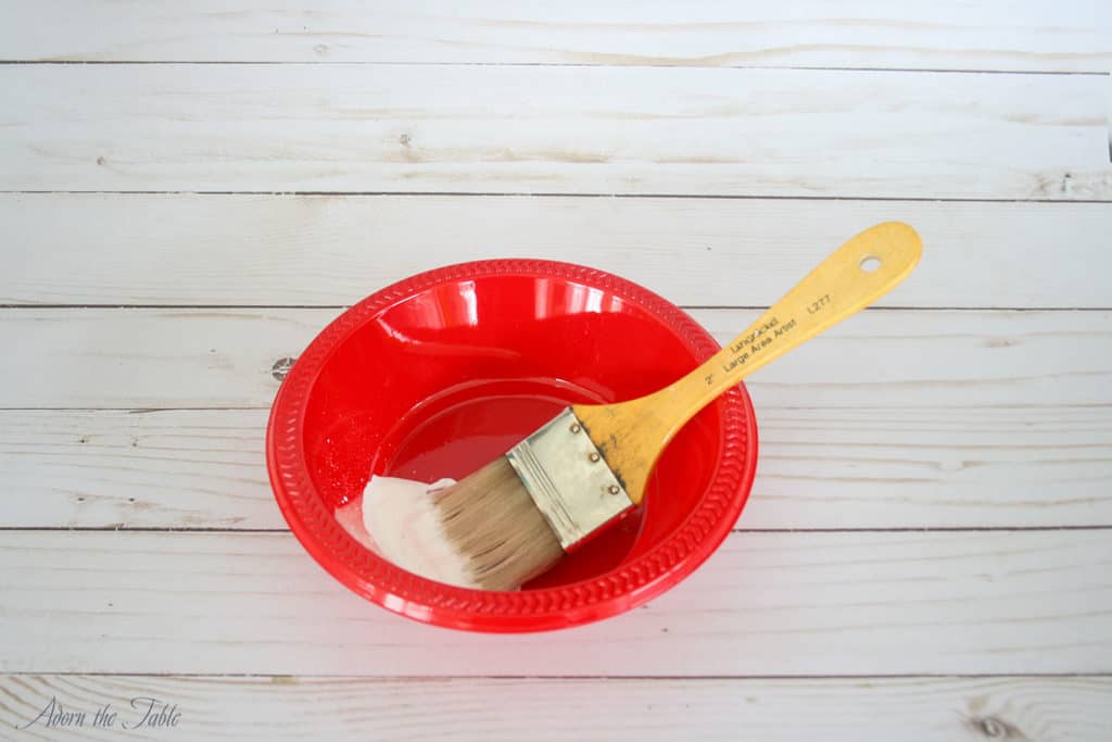 red bowl with white paint and toothbrush inside