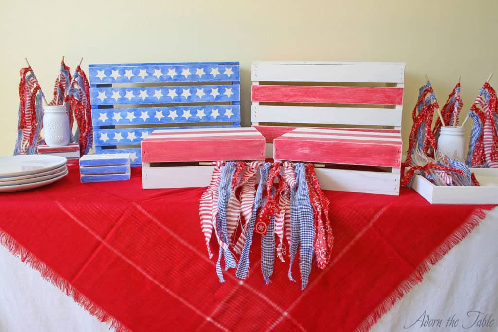 Completed memorial day buffet table with red scarf, wooden diy crates and diy ripped fabric flags