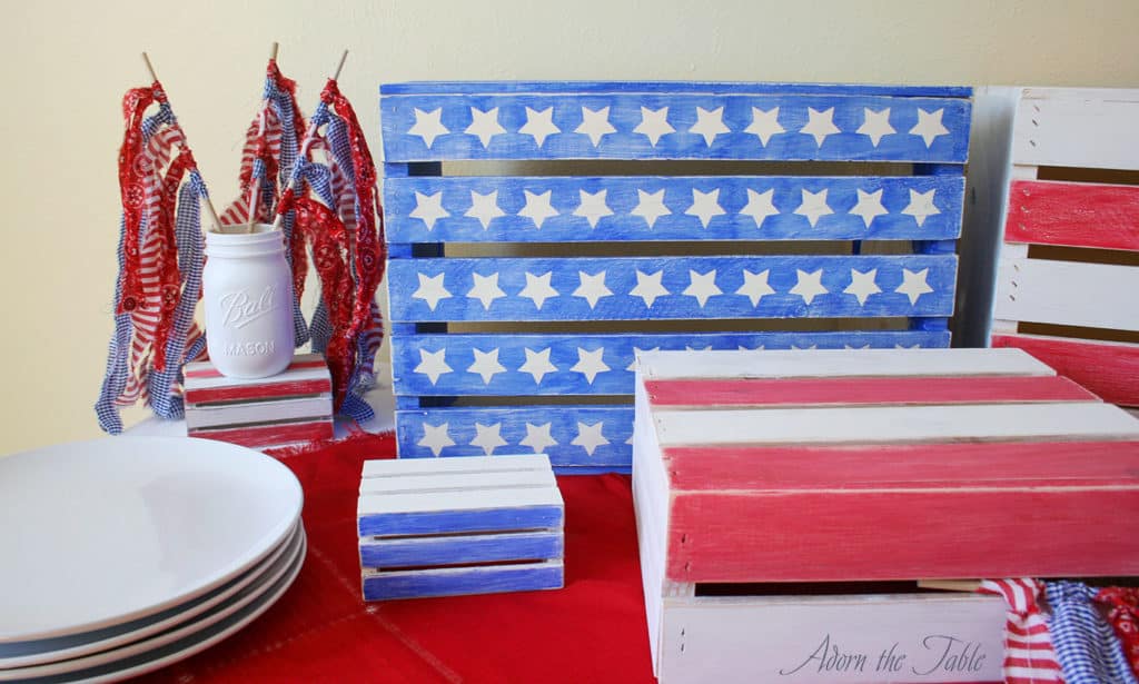 Left side view of memorial day buffet with white plates stacked and wooden crates