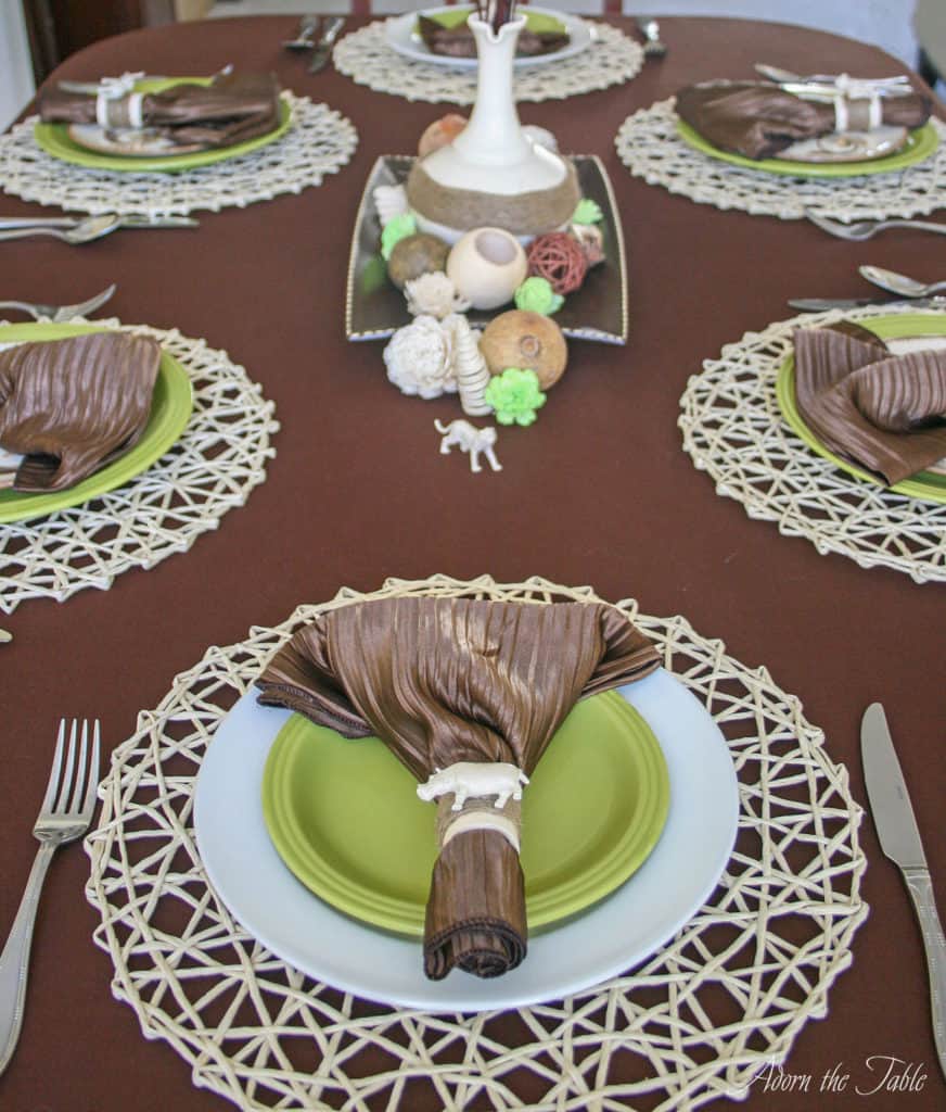 overhead view of safari table setting with hippo napkin ring and centerpiece in the distance