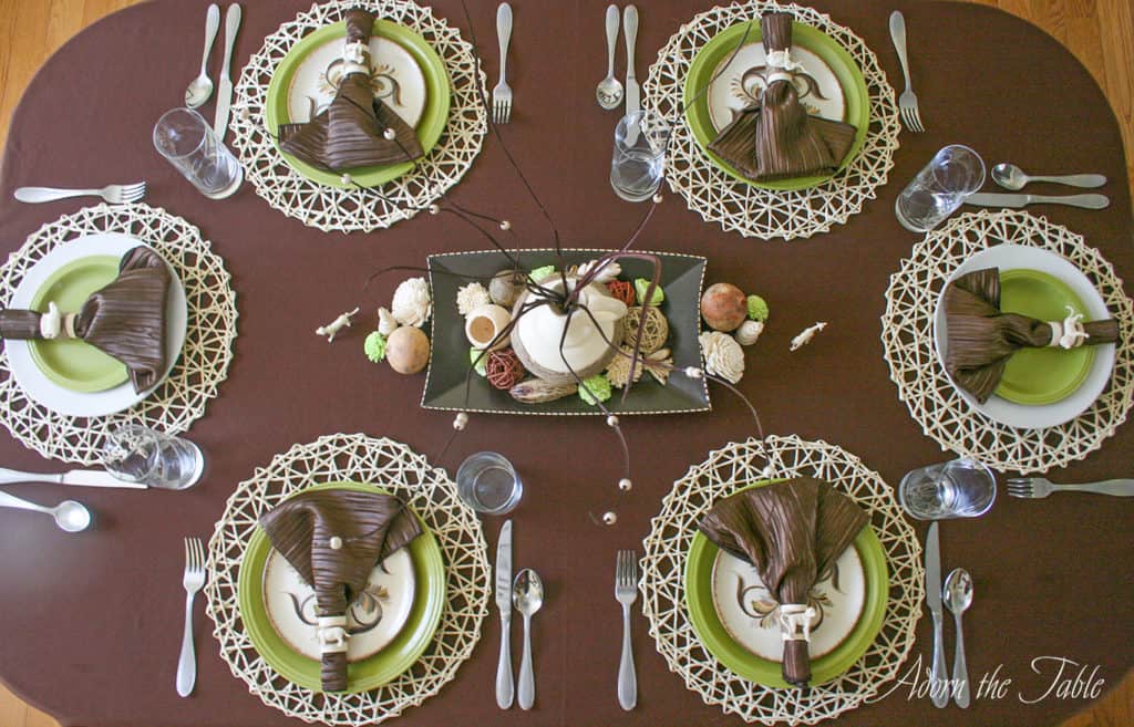 closeup overhead view of table setting with brown tablecloth, safari place settings and diy centerpiece