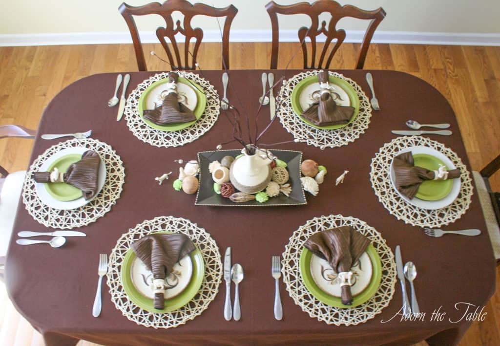 overhead view of table setting with brown tablecloth, safari place settings and diy centerpiece