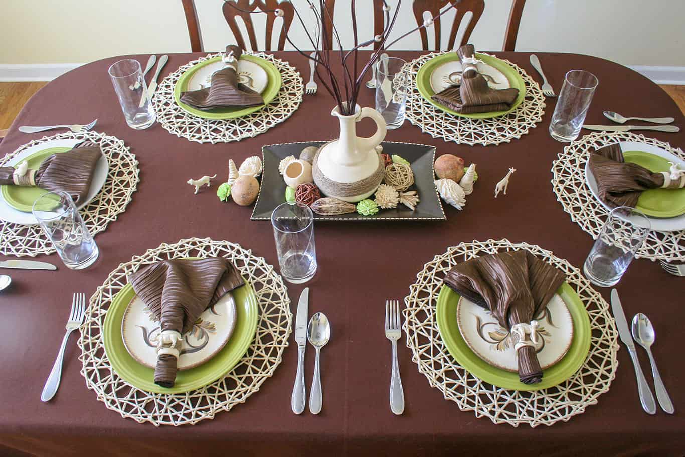 Safari table setting. Overhead view of table with brown tablecloth and safari themed place settings