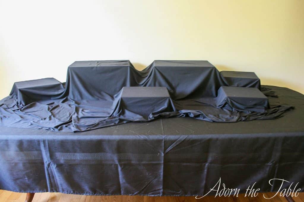Graduation buffet table with black base fabric, and crates hidden with more black fabric