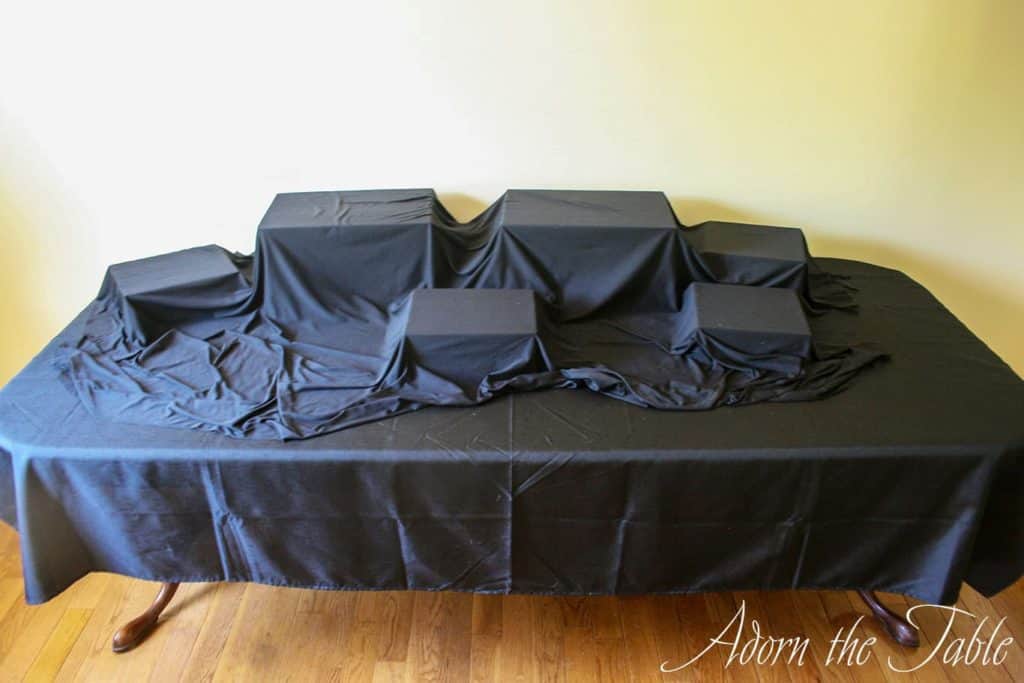 Graduation buffet table with black base fabric, and crates hidden with more black fabric