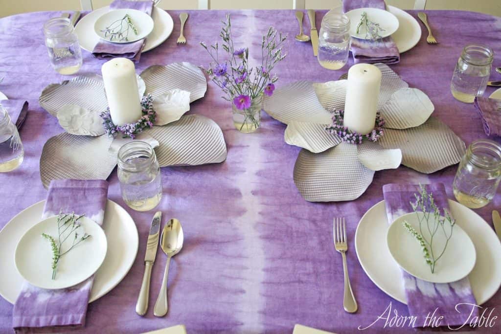 Angled view of boho table setting with lilac and white tablecloth and cookie sheet diy flowers