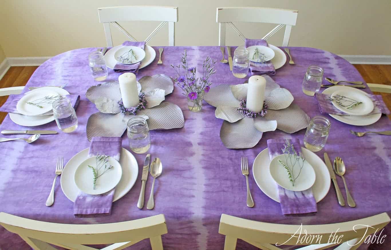Side view of boho table setting in lilac and white. With tie-dyed tablecloth and mason jars.
