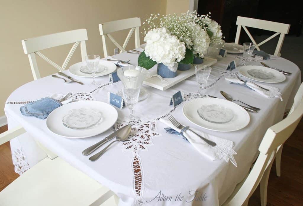 Corner view of denim and white lace table setting.