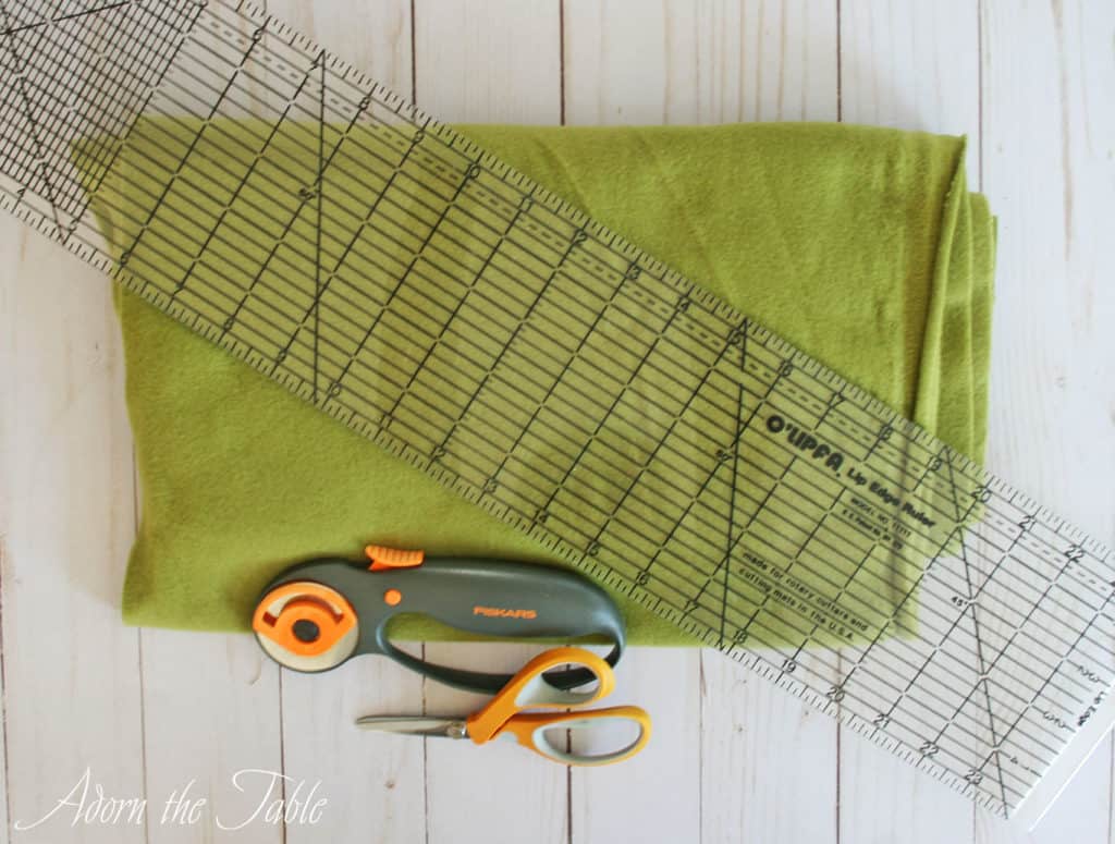 DIY felt placemat supplies. Green fleece, clear ruler, rotary cutter and scissors.