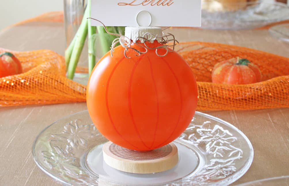 Unique pumpkin place card holder on fall-themed table setting.