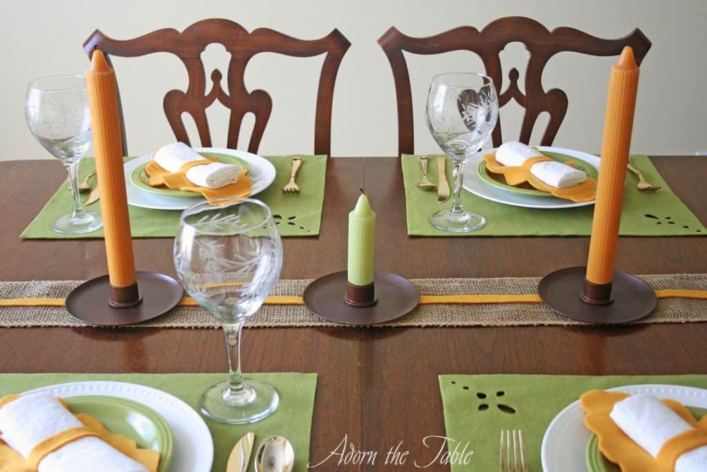 Fall table setting with green fleece placemats and orange napkin holders.