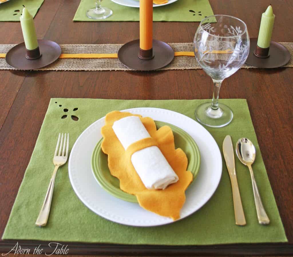 Fall place setting with green placemat and orange napkin ring.