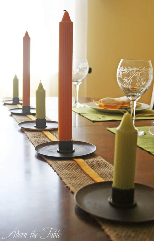 Green and orange candles on fall-inspired table setting.