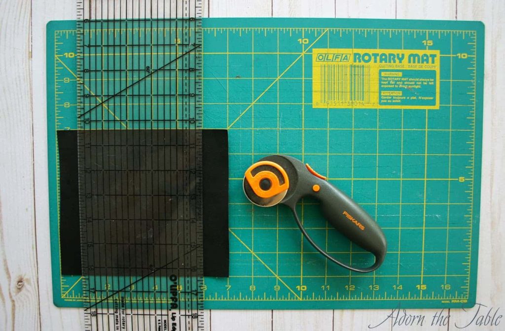 Black faux leather on cutting mat with clear ruler and rotary cutter. 