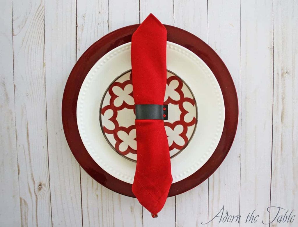 Diy faux napkin ring around red napkin. On set of red and white dishes.