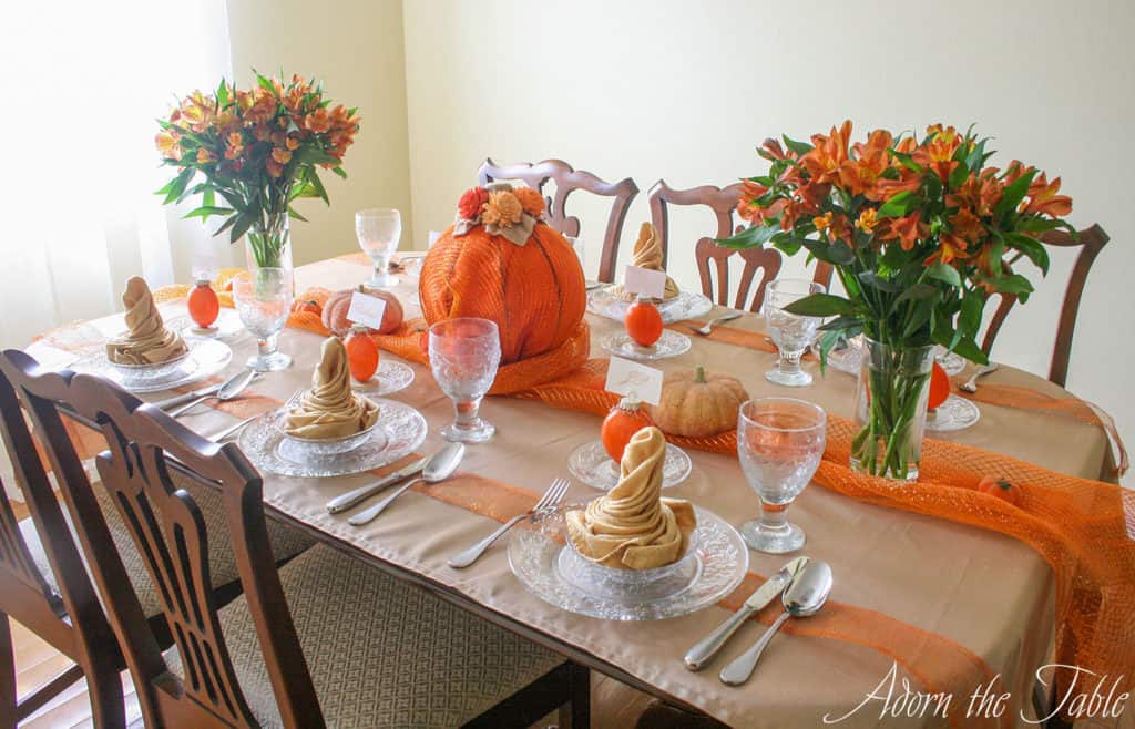 Right side of table setting for autumn using clear places, pumpkin place card holders, orange flowers and pumpkins