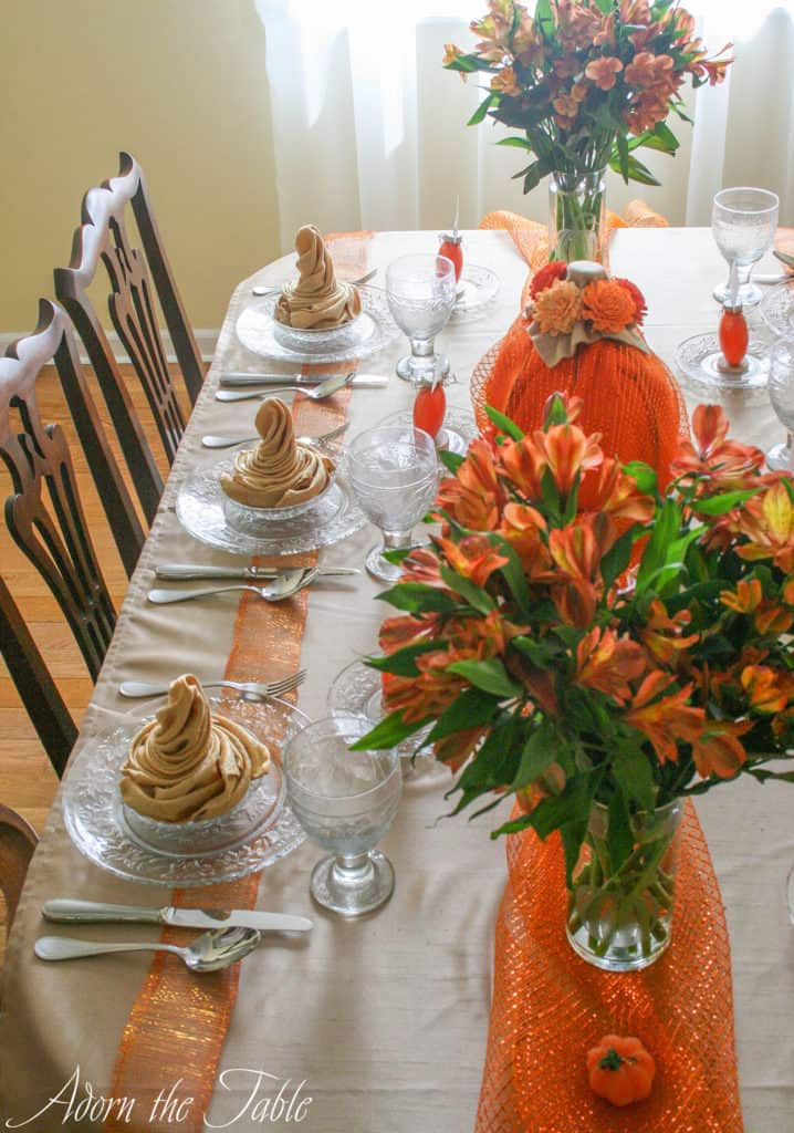 Overhead, left side view of pumpkin table setting with orange mesh down the middle