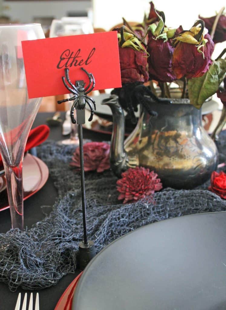 Spider-place-card-holder on Halloween table with red name card.