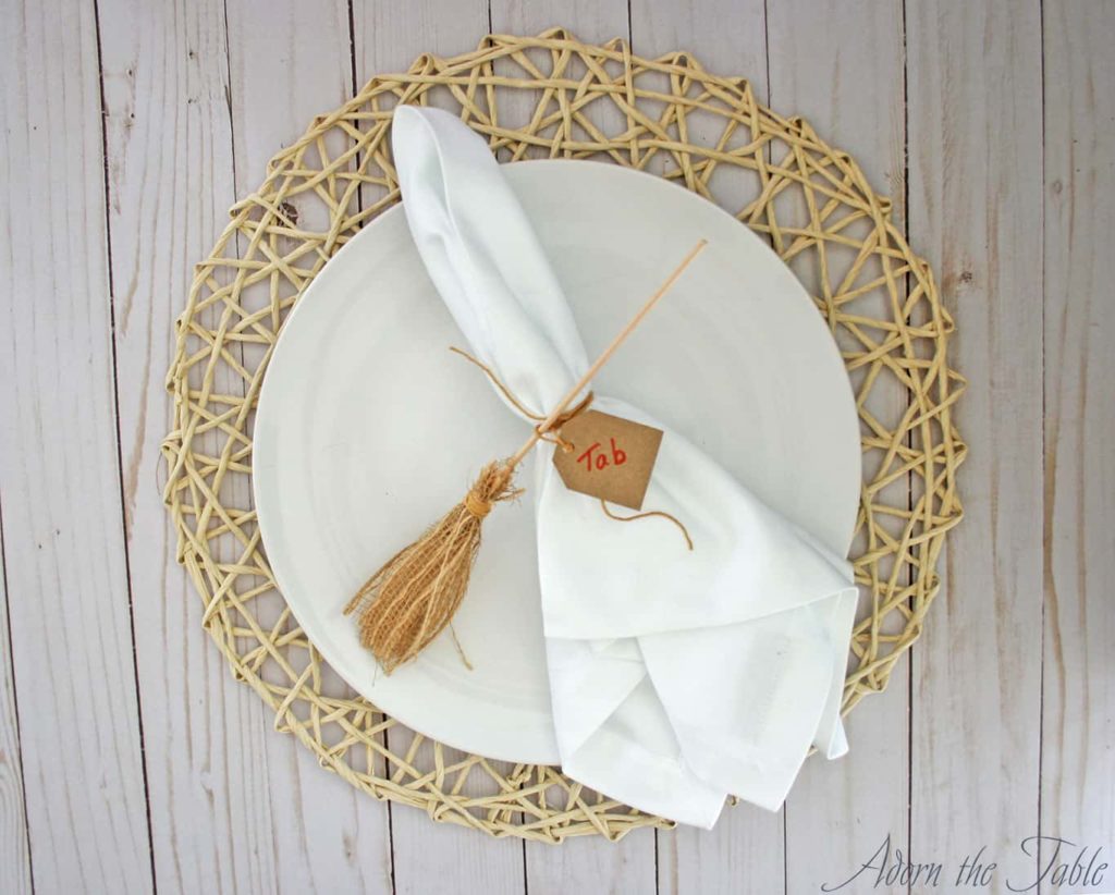 DIY Witch's Broomstick place card holder on white napkin and white plate.