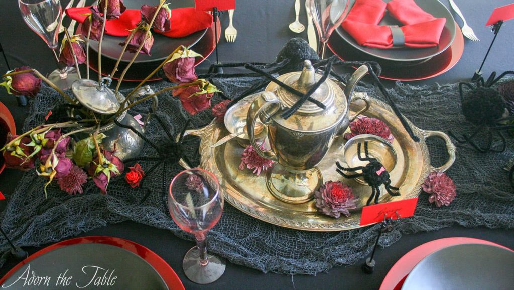 Overhead view of creepy halloween tablescape with fake spiders and tarnished silver.
