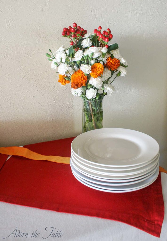Red, orange and white flowers in vase on a minimalist Thanksgiving day buffet