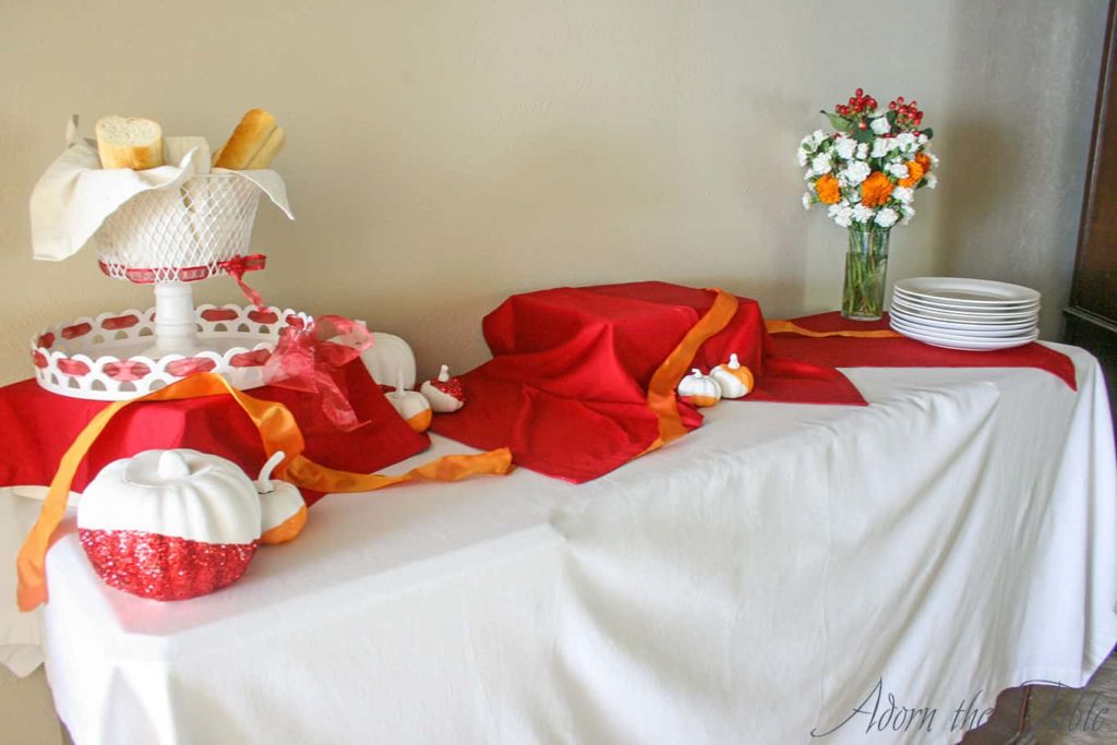 Chic minimalist Thanksgiving day buffet with red napkins and orange ribbon.