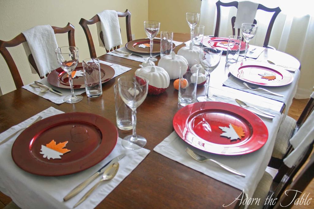 Thanksgiving Day table from the head of the table with red chargers and glasses.
