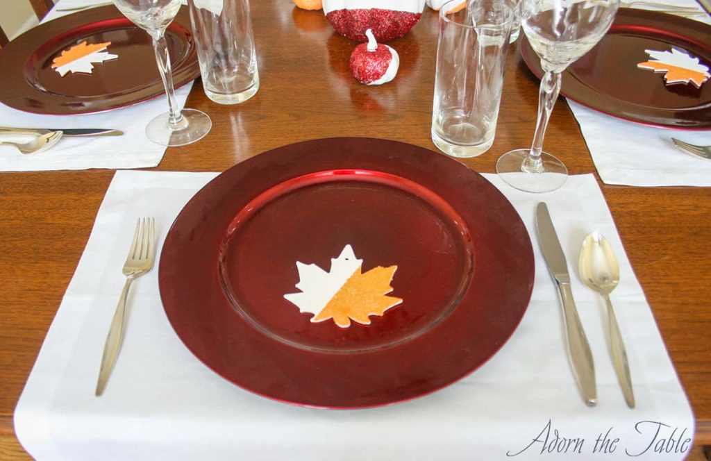 Simple Thanksgiving day place setting with red charger and silver flatware. 