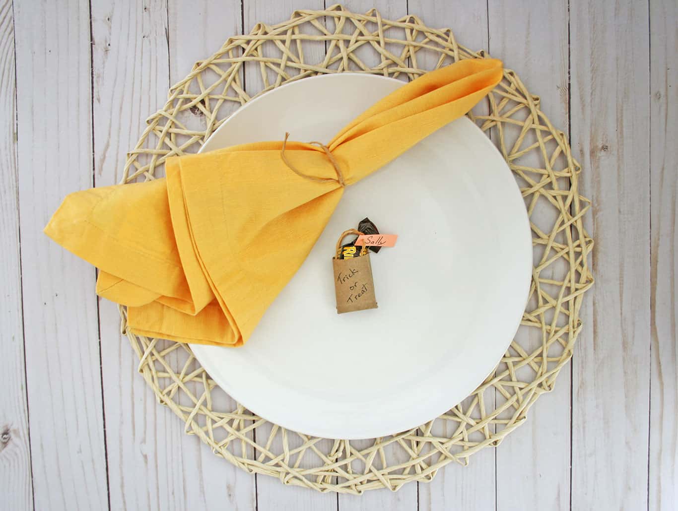 Small diy trick or treat paper bag on white plate next to yellow napkin