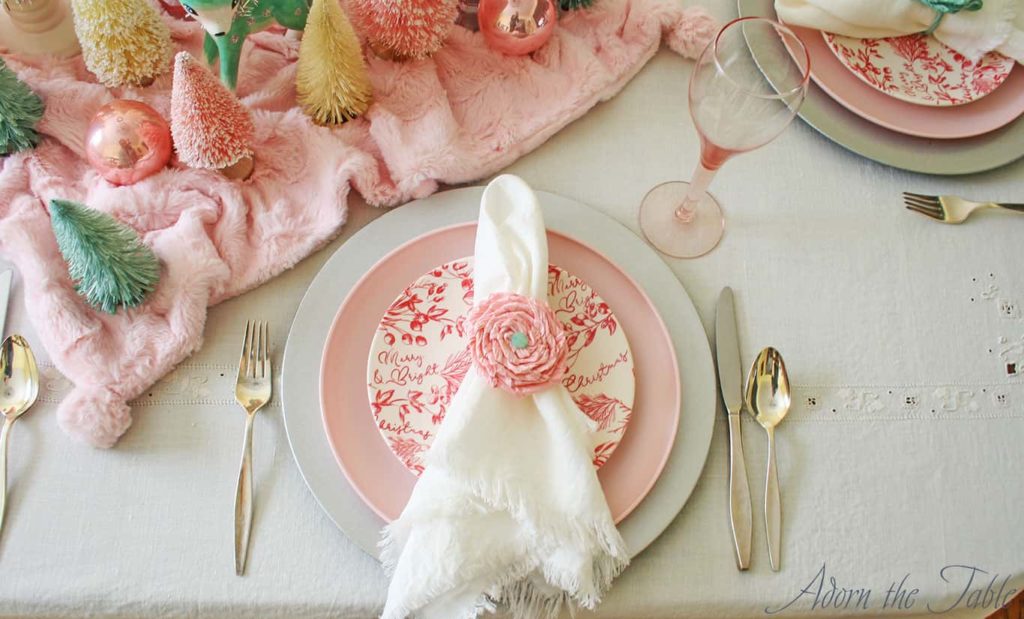 Place setting with silver charger, pink plate, red and cream salad plate and white napkin with pink napkin ring.