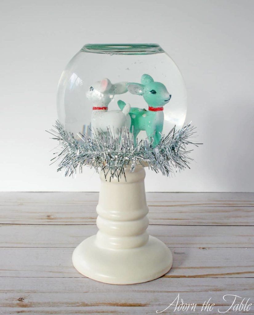 Snow globe with reindeer inside and tinsel wrapped around outside