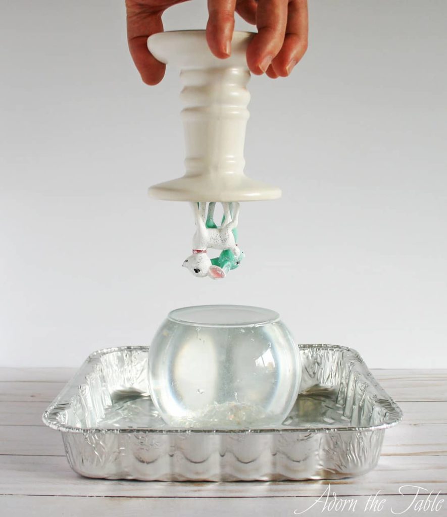 Candle holder upside down over water filled vase.