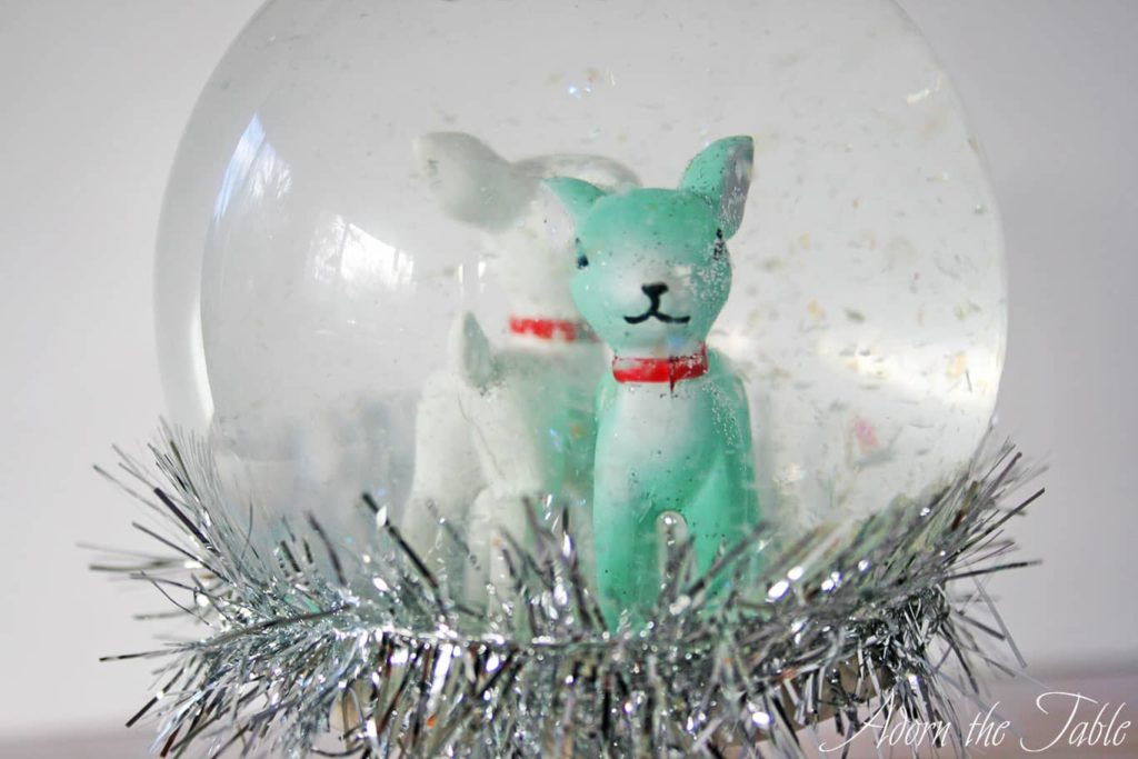 Close up of reindeers inside the diy snow globe with the fake snow falling.