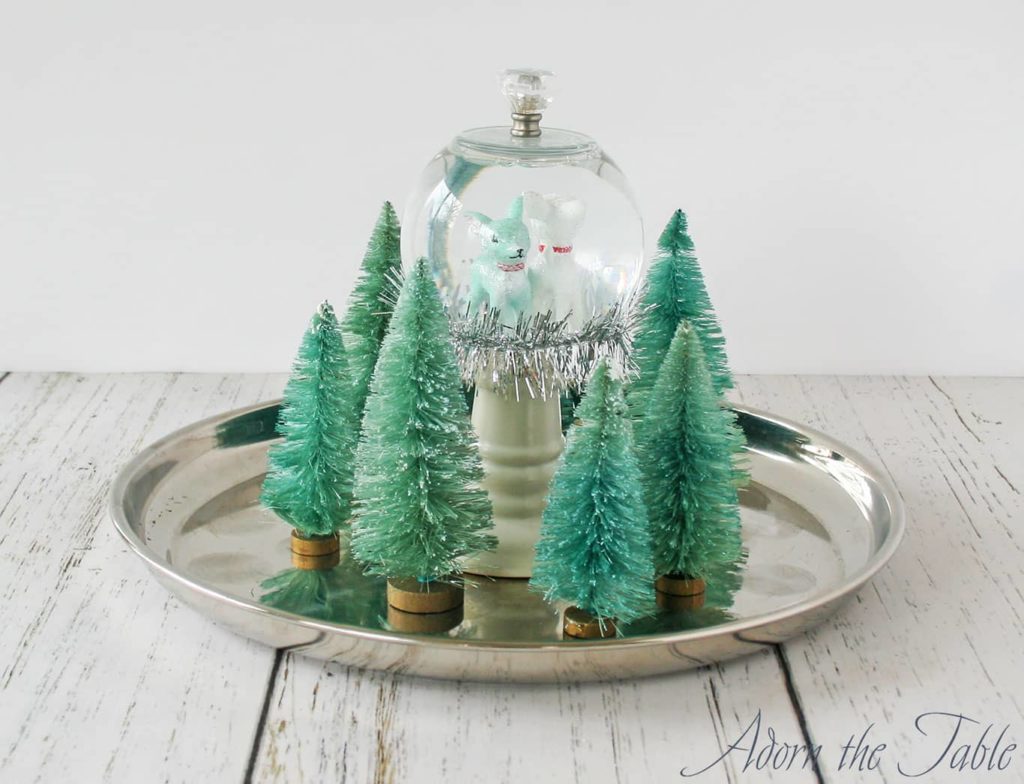 Silver tray with green trees and snow globe