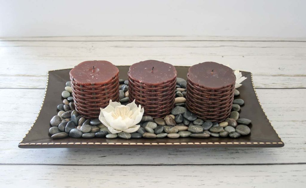 Brown candles inside platter with pebbles.