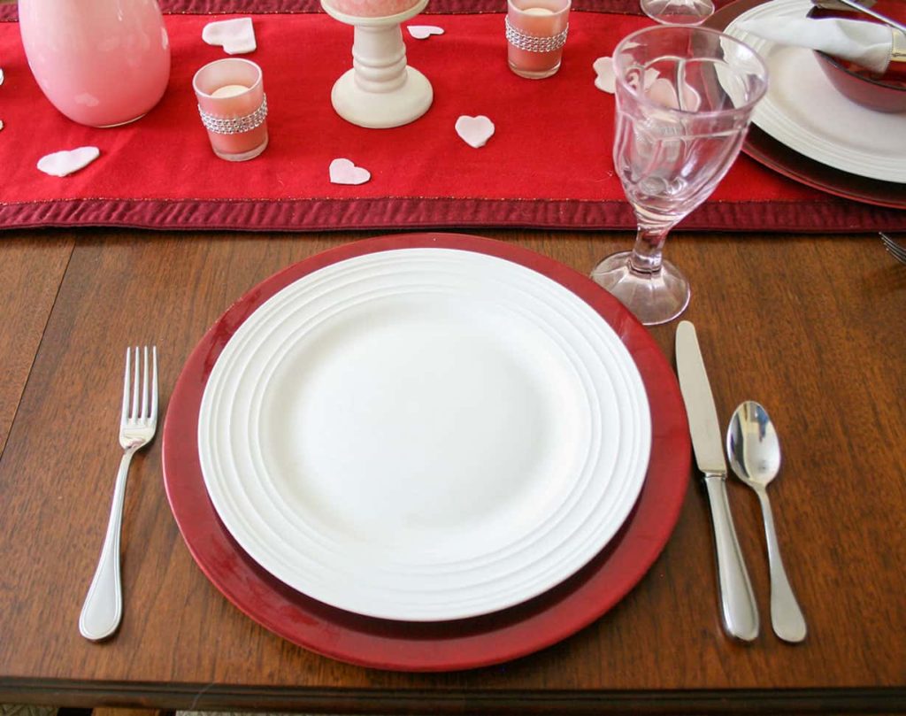 Place setting of red charger and white plate