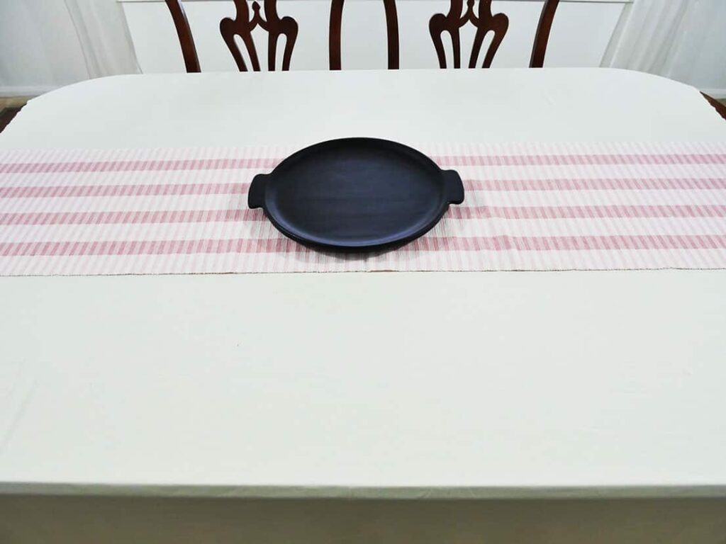 Black round platter on table runner
