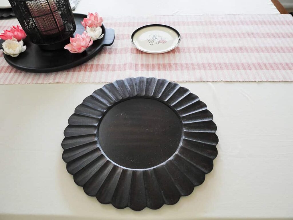 Scalloped black wood chargers on tablecloth