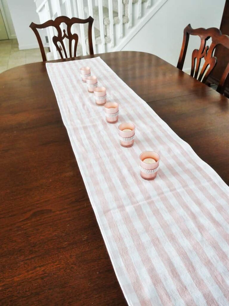 Row of pink votive candles on checkered runner