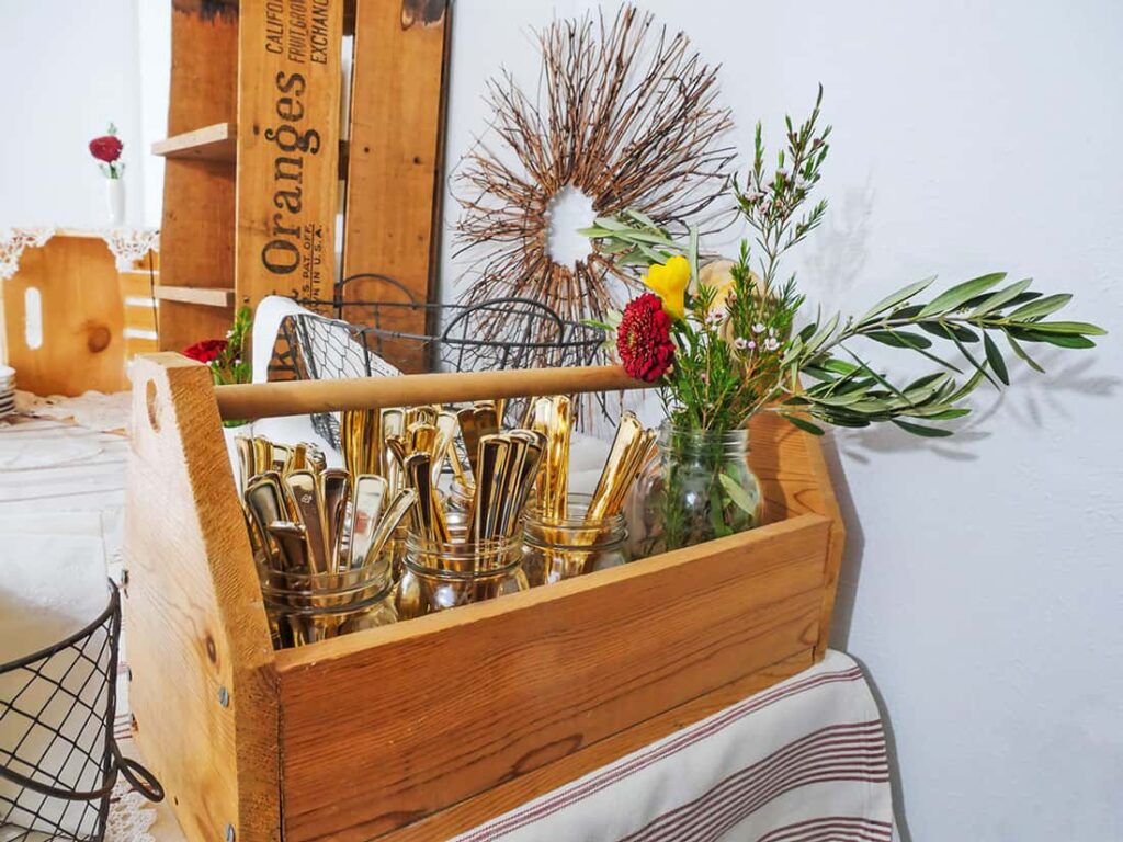 Wooden toolbox filled with utensils on rustic farmhouse buffet table setup