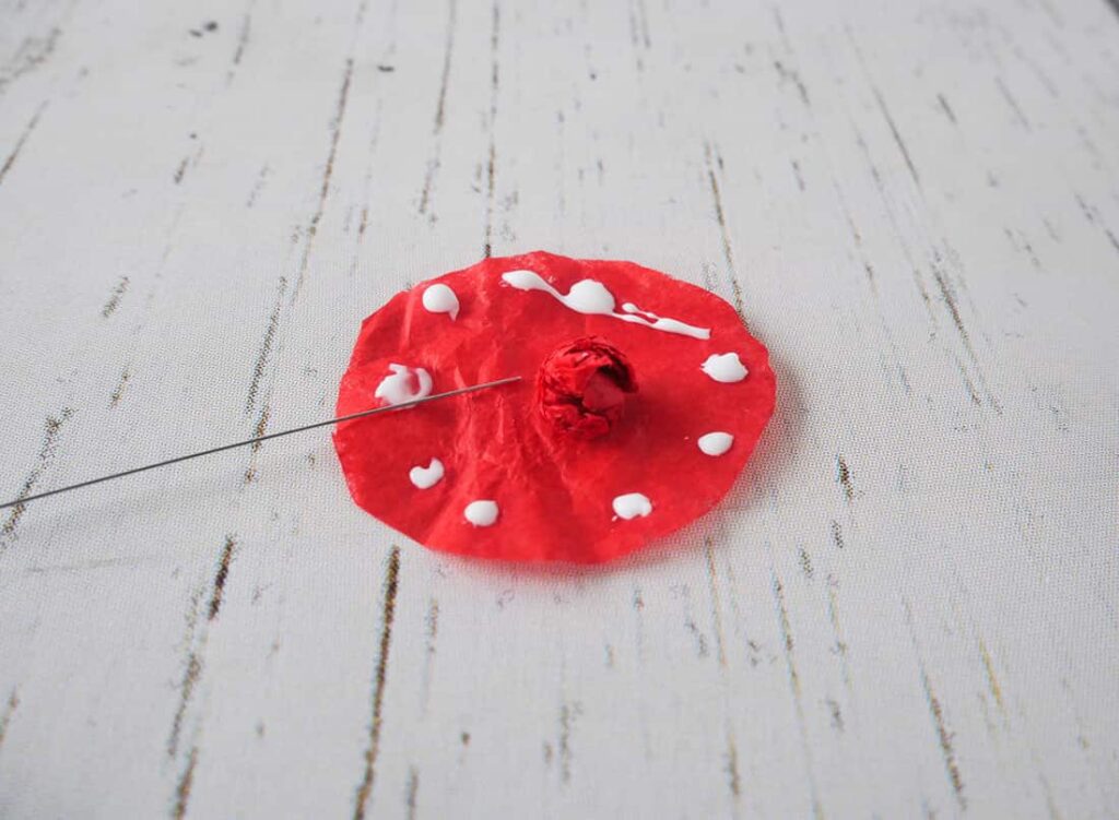 Red circle with ball of tissue paper in center for DIY red poppy napkin rings 