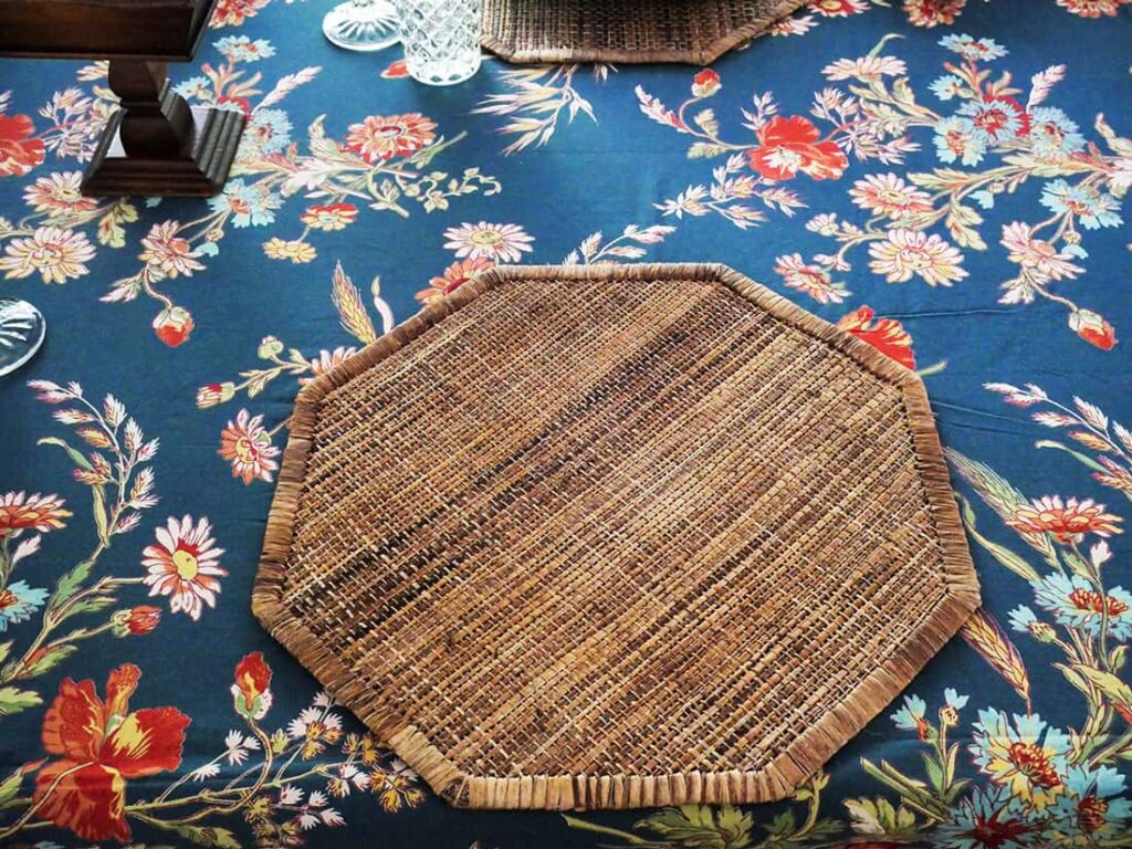 Woven placemat on top of floral tablecloth
