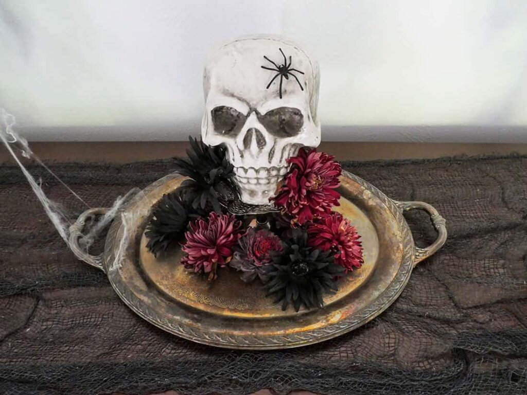 Close up of skull on tray surrounded by flowers.