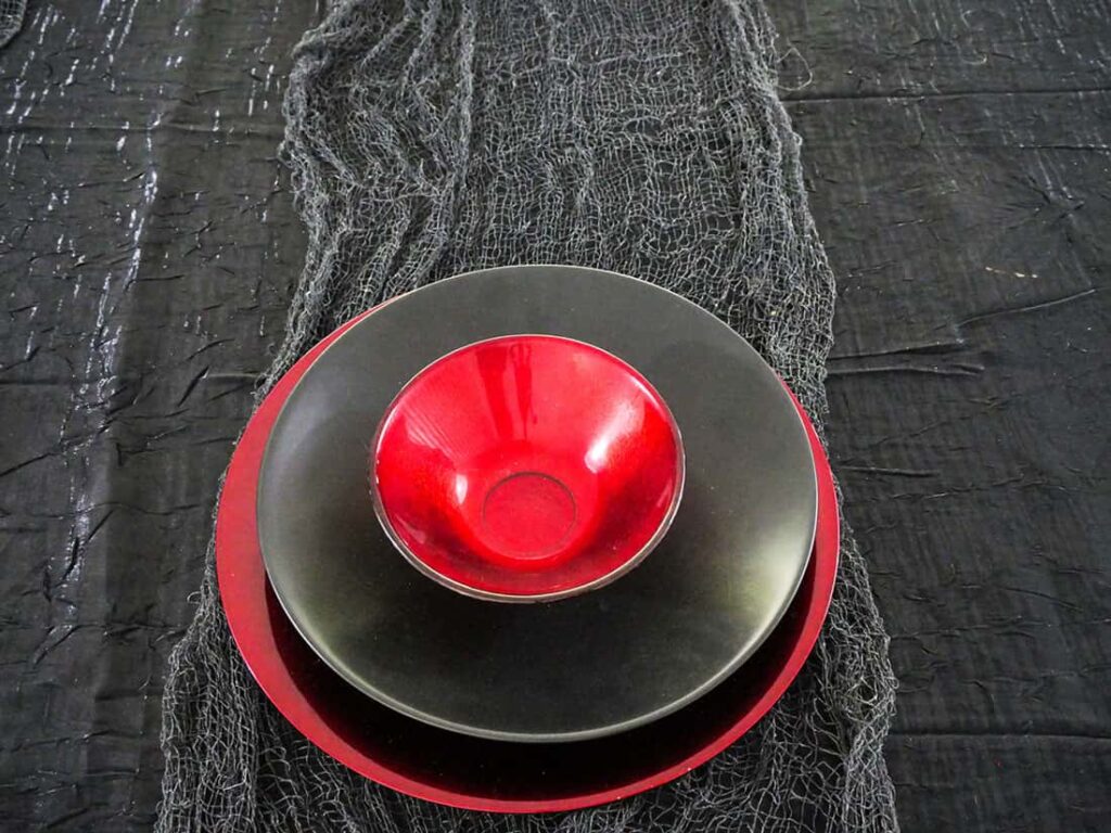 Red bowl on black plate.