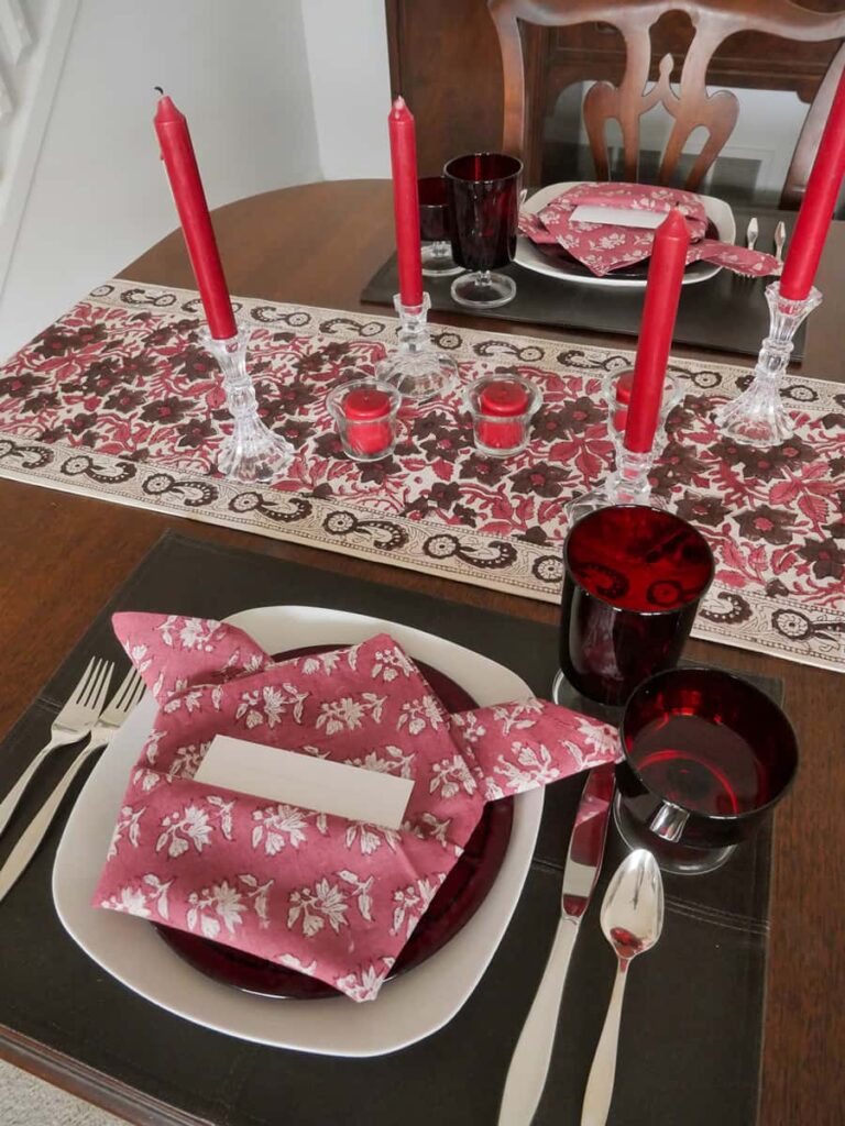 Full view of romantic table setting for two in red and brown.